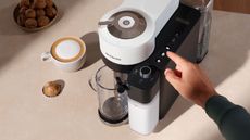 How to use a Nespresso machine: A birdseye view of the Nespresso lattissima one coffee maker on a countertop with coffee and a pod at the side