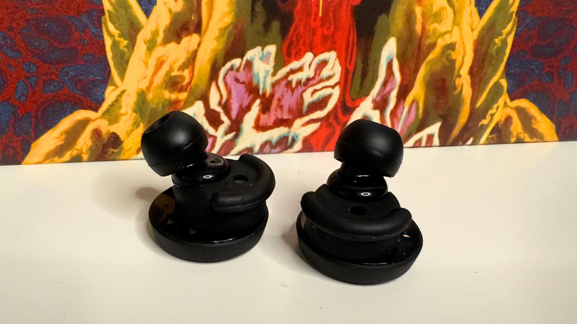 Denon PerL earbuds side by side in front of a record