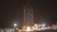 A tall finned black rocket fires an engine on a test stand in the black of night.