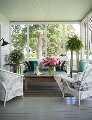 porch seating area with white rattan chairs and wooden coffee table