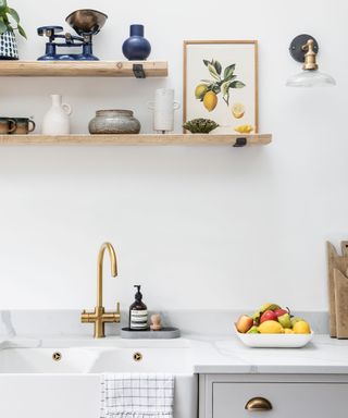 Detail of kitchen sink with gold tap and open shelving above