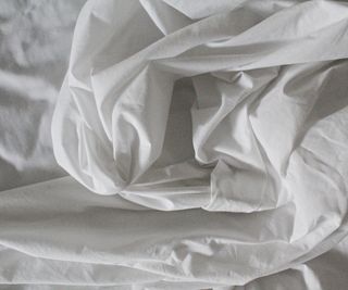 Dishevelled white bedding on a bed