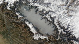 A satellite photo of giant lake of smoky haze filling a large valley surrounded by mountians