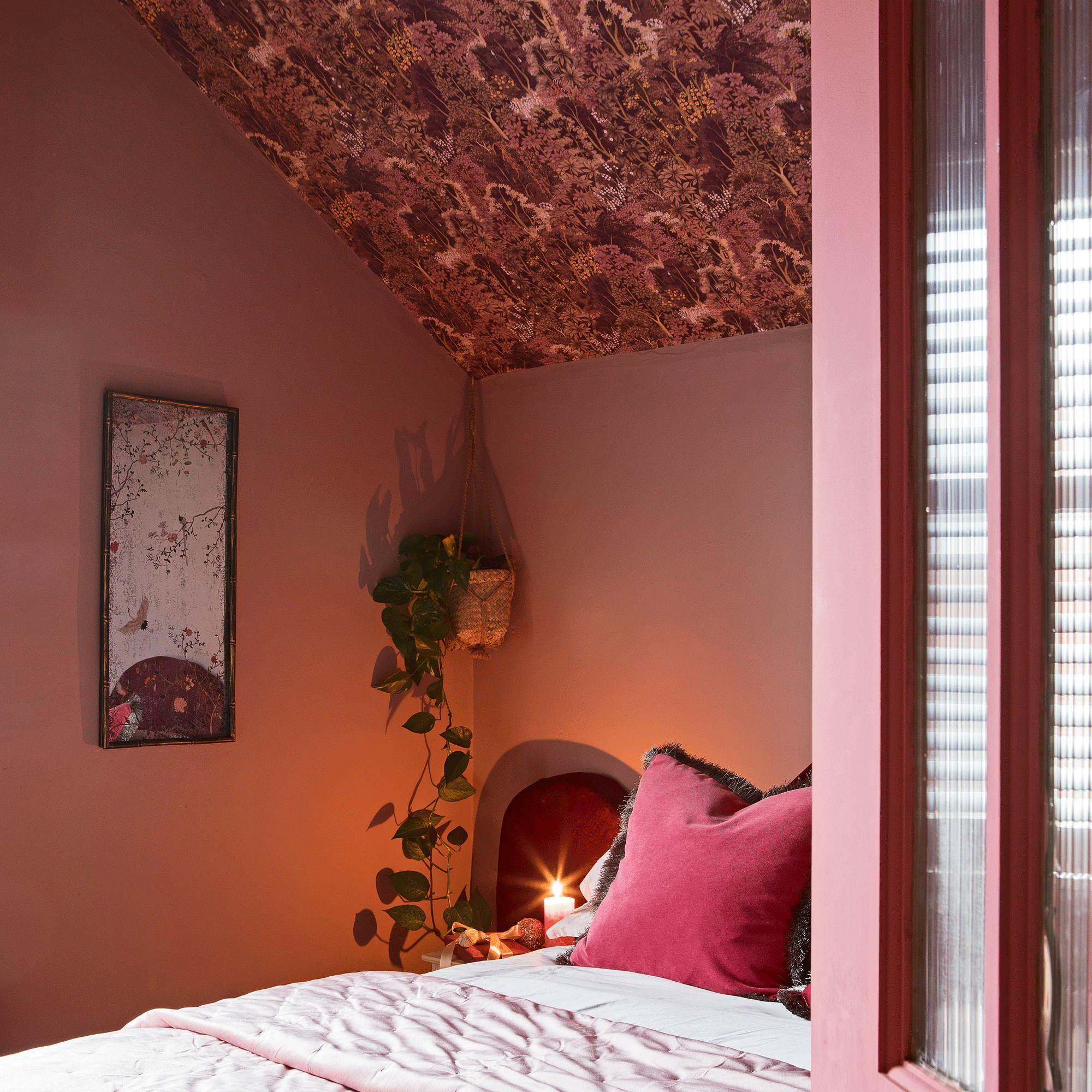 a loft bedroom with pink walls and a wallpaper covered sloped ceiling