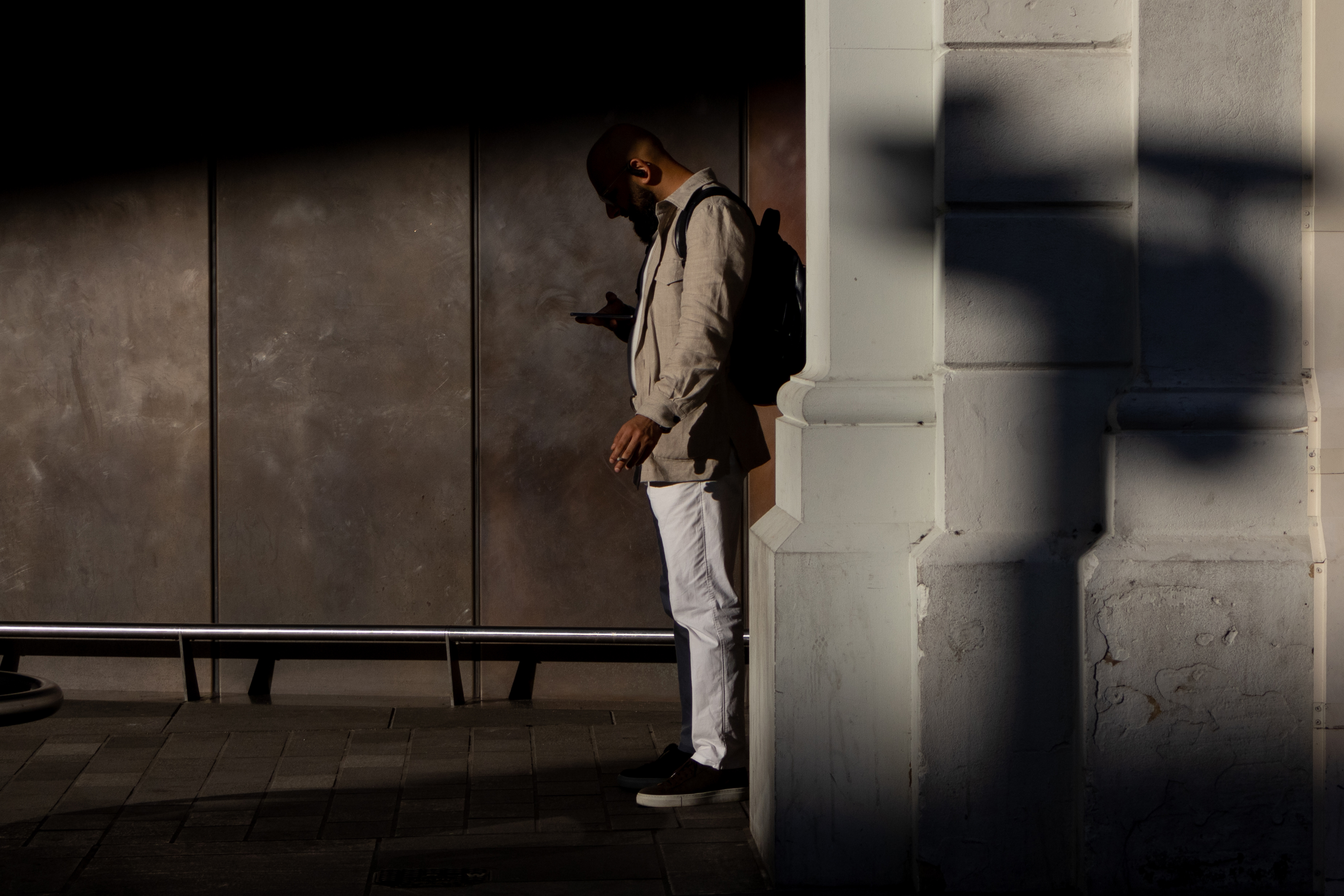 A man standing in the shade looking at his phone