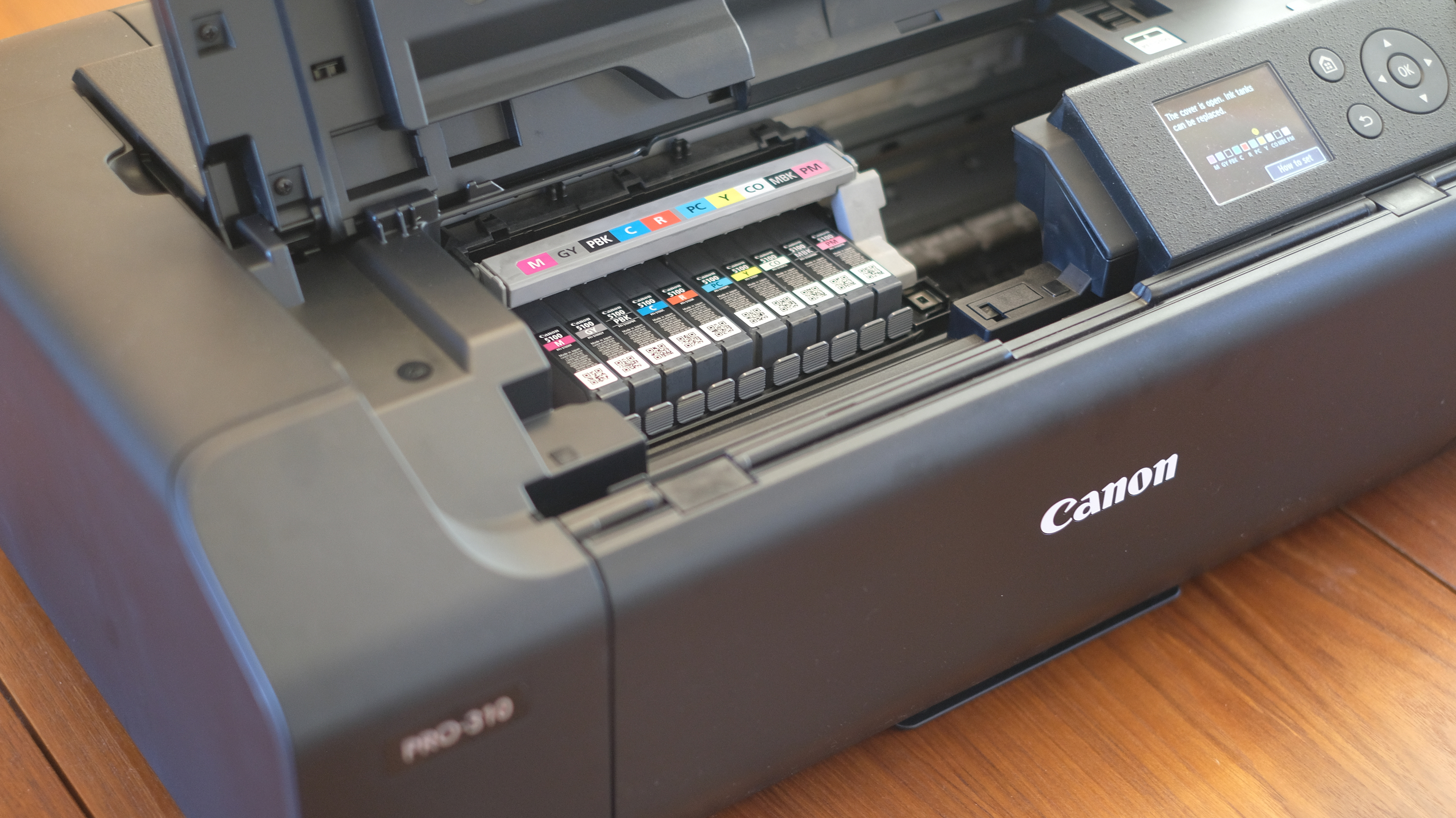 A photograph of the Canon imagePROGRAF PRO-310 printer with chassis open and ink tanks visible