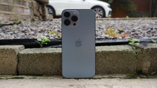 En iPhone 13 Pro Max stående utendørs, sett bakfra