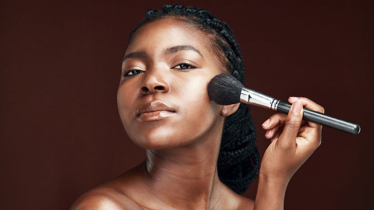 best setting powder - woman using a makeup brush on her cheek - getty 1389918172