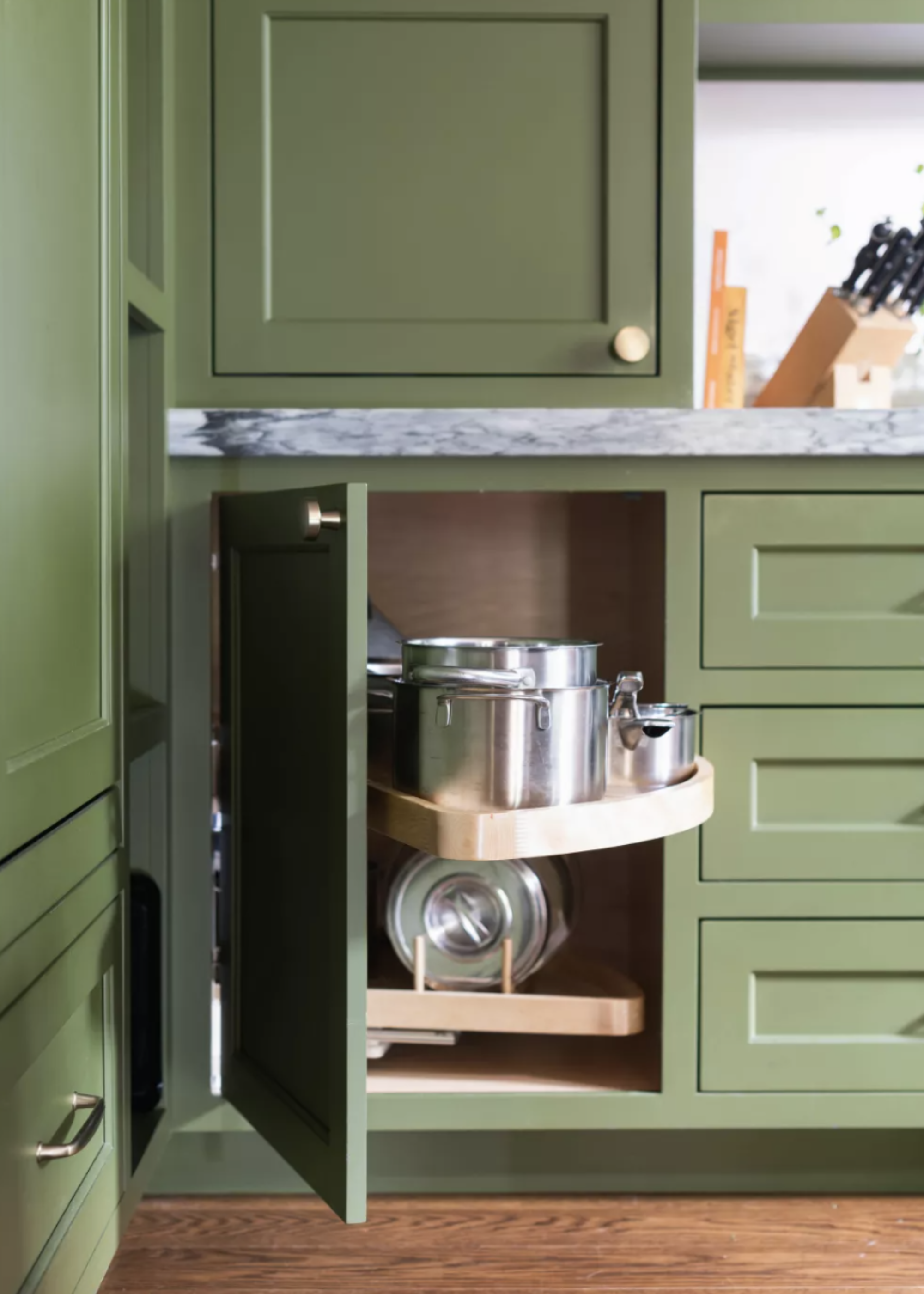 green kitchen corner cabinets without pull out storage by BLDC Design with pots and pans on top of the pull out drawers
