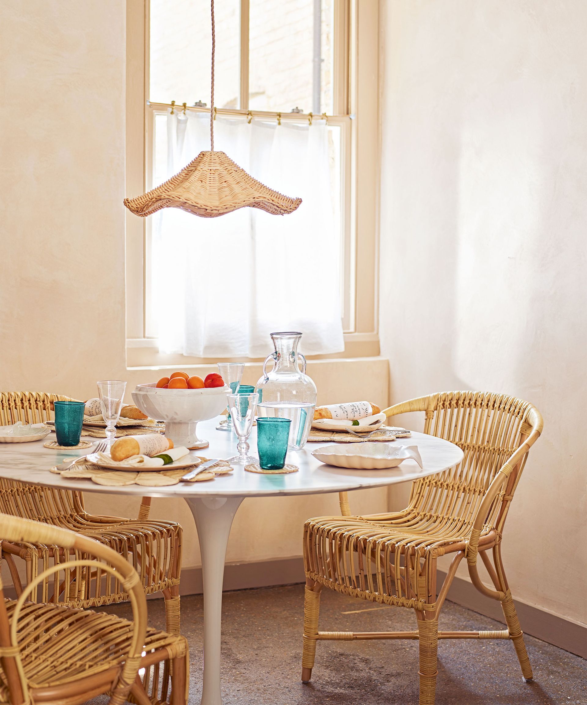 Rustic dining area filled with natural materials, wicker pendant and dining chairs, round marble dining table