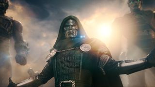 Doctor Doom (Downey jr) stands in his iconic green robe and armor, arms stretched out, sentinels looming over his shoulder in Avengers: Doomsday (2026).