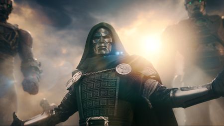 Doctor Doom (Downey jr) stands in his iconic green robe and armor, arms stretched out, sentinels looming over his shoulder in Avengers: Doomsday (2026).