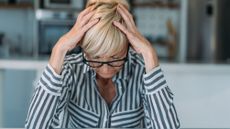 An older woman holds her head like it hurts.