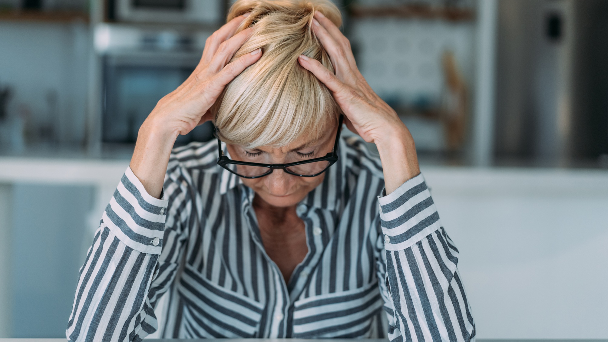 An older woman holds her head like it hurts.