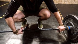 A man preparing to lift a barbell with weightlifting straps