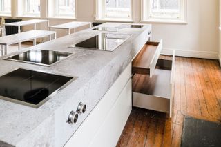 Grey kitchen island with cooking plates and white and brown wooden doors