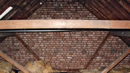attic with wooden beam and brick wall