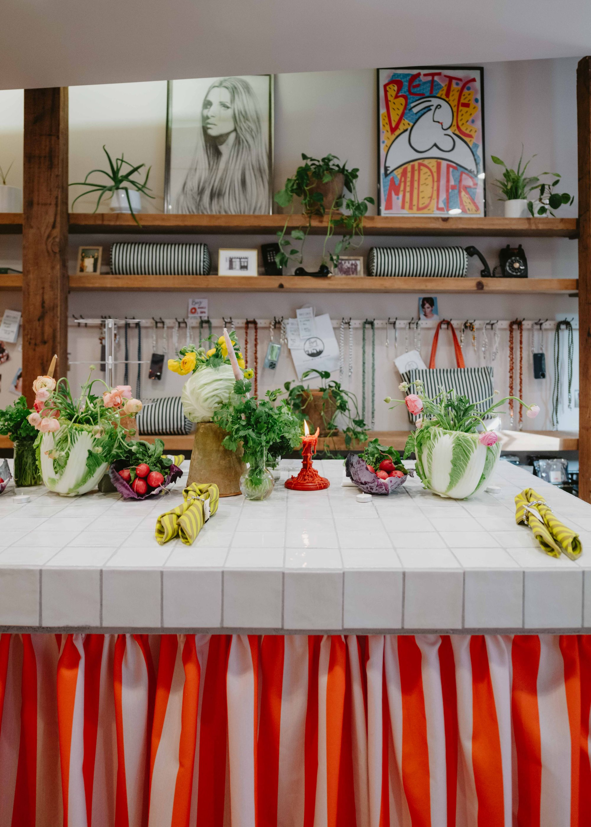 a white tiled counter with miscellaneous objects on top and a fabric skirt in red and pink