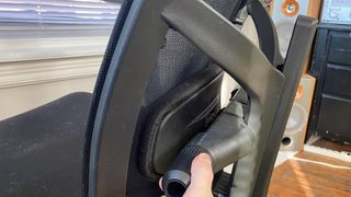 A hand adjusting the lumbar support on an office chair