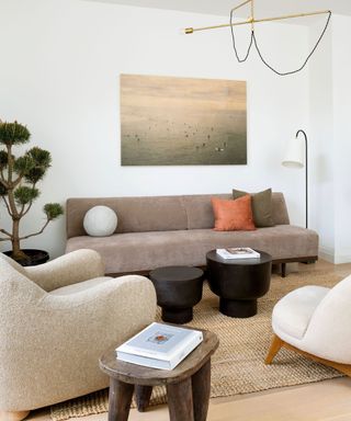 living room with taupe sofa, two cream armchairs and multiple side tables