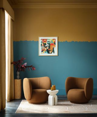 living room painted in dark teal and ochre yellow with a raw edged paint border around top half of wall