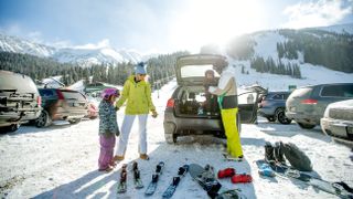 family at a parking lot unloading ski and snowboard equipment out of their car