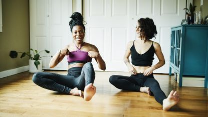 Female friends laughing together during yoga workout in home