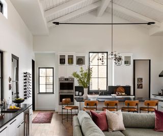 family room with gray sofa and kitchen with bar stools in background and bar behind