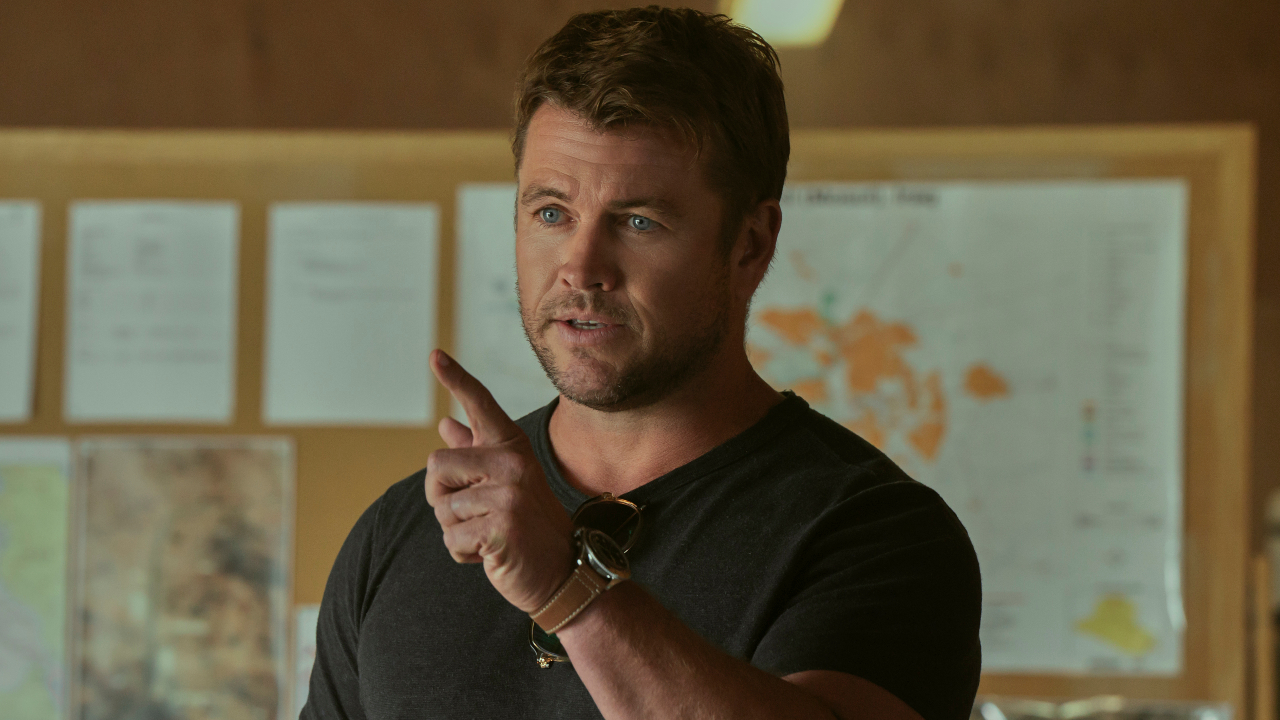 Luke Hemsworth points forward while standing in a briefing room in The Terminal List: Dark Wolf. 