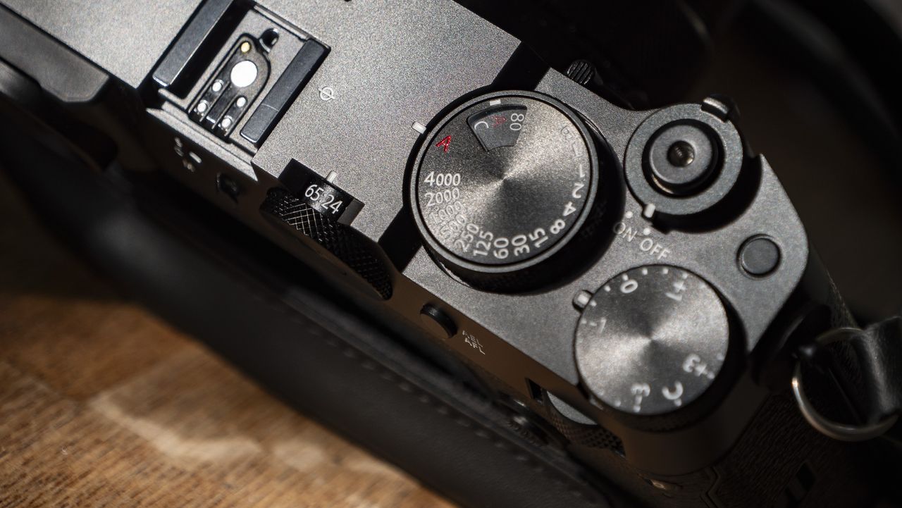 All-black Fujifilm GFX100RF rangefinder-style camera on a wooden table