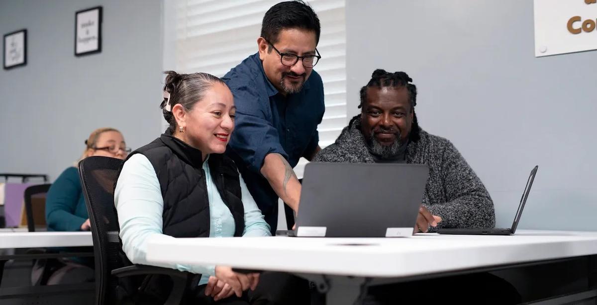 Man training two people using a laptop