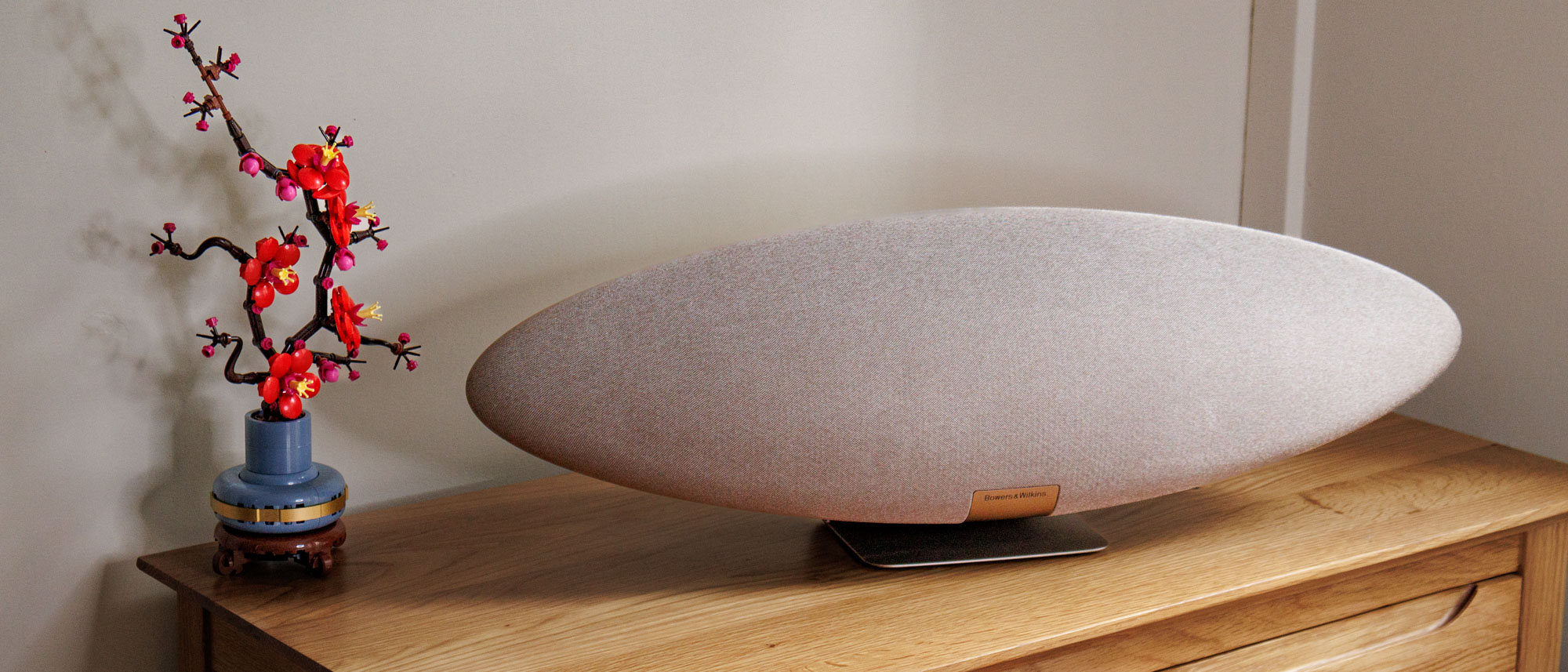 Zeppelin Pro speaker on a wooden surface next to a lego flower