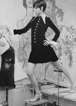 A fashion model stands on a table and a chair as she poses for a portrait in the studio of designer Betsey Johnson, New York, September 6, 1966