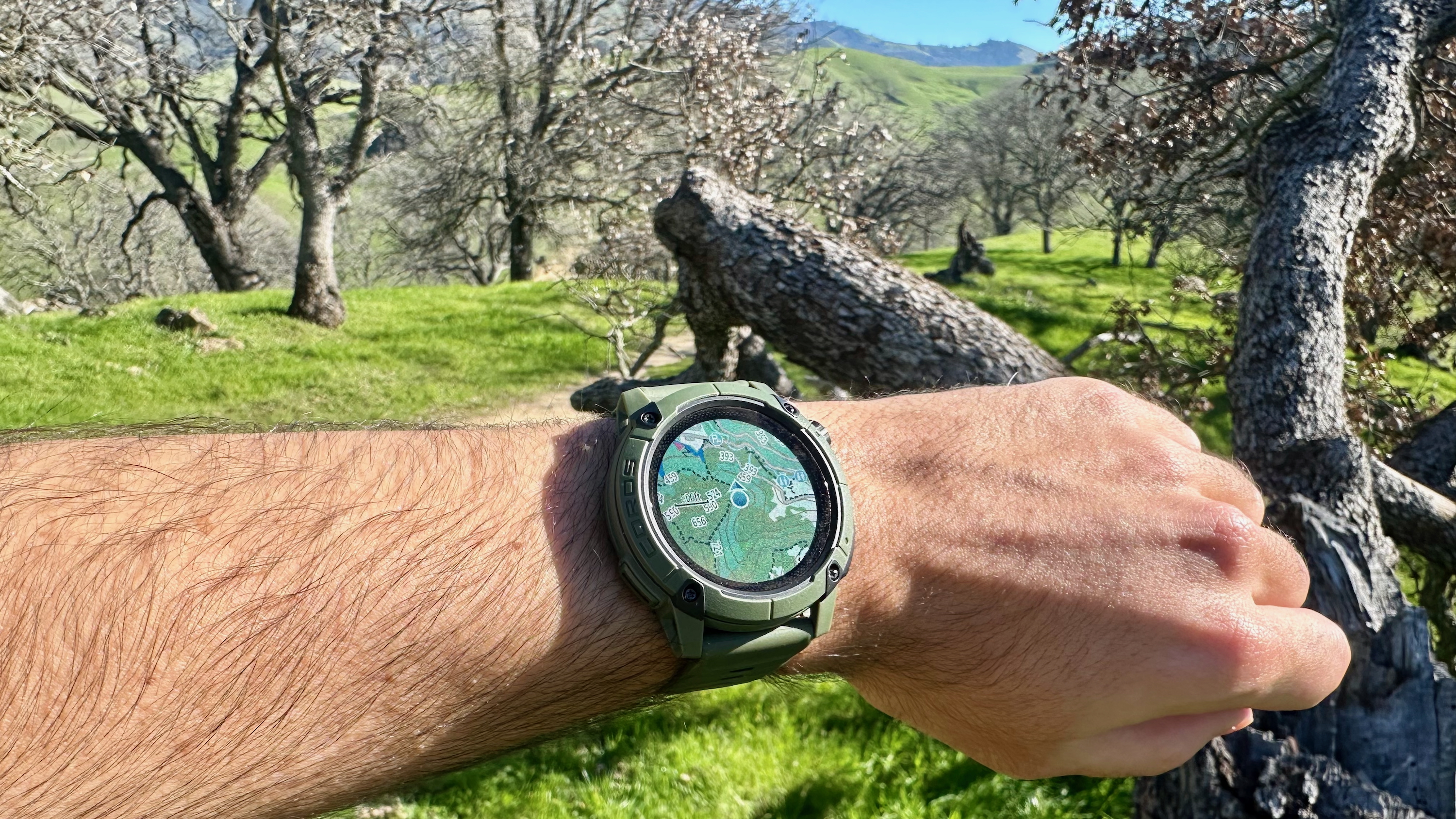 Photo of the COROS NOMAD with the map active and a green trail path behind it.