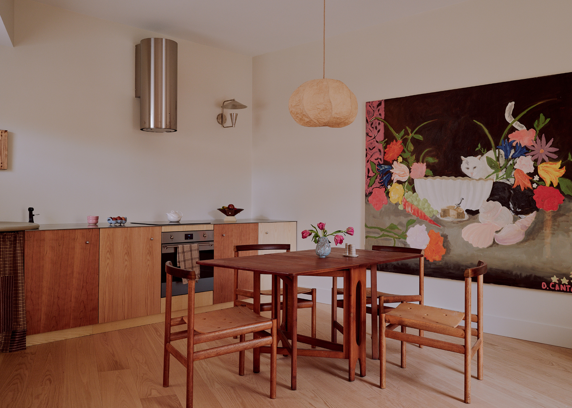 modern kitchen with wooden cabinetry, a chrome oven hood, and a crafted wooden dining table
