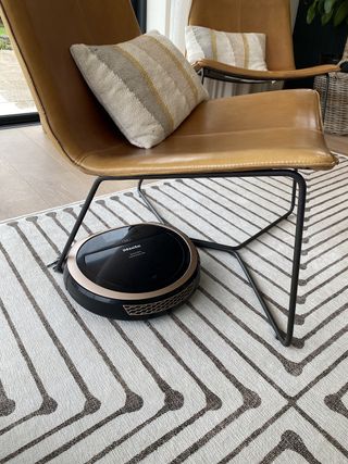 Miele vacuum cleaner on a striped rug next to a leather chair