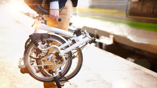 Man holding a folding bike at train station