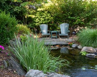 Large backyard with gravel patio, pond, and Adirondack chairs