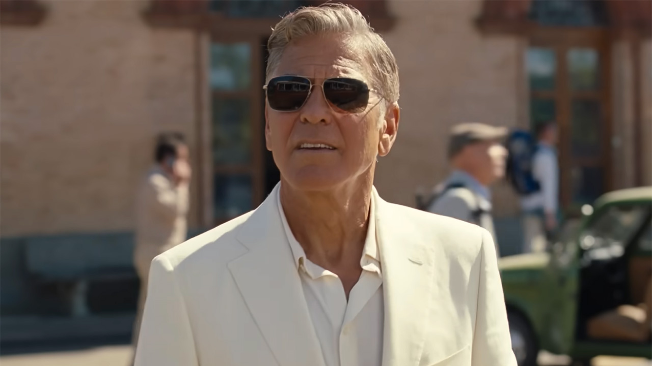 Jay Kelly actor George Clooney in a white suit and sharp shades staring into the distance.
