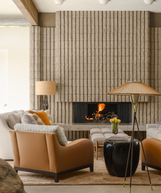 Desert hues in living room with leather armchairs at fire surround with groove wall detailing