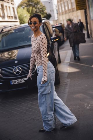 A woman at Fashion Week wearing a Marine Serre moon top and blue baggy jeans