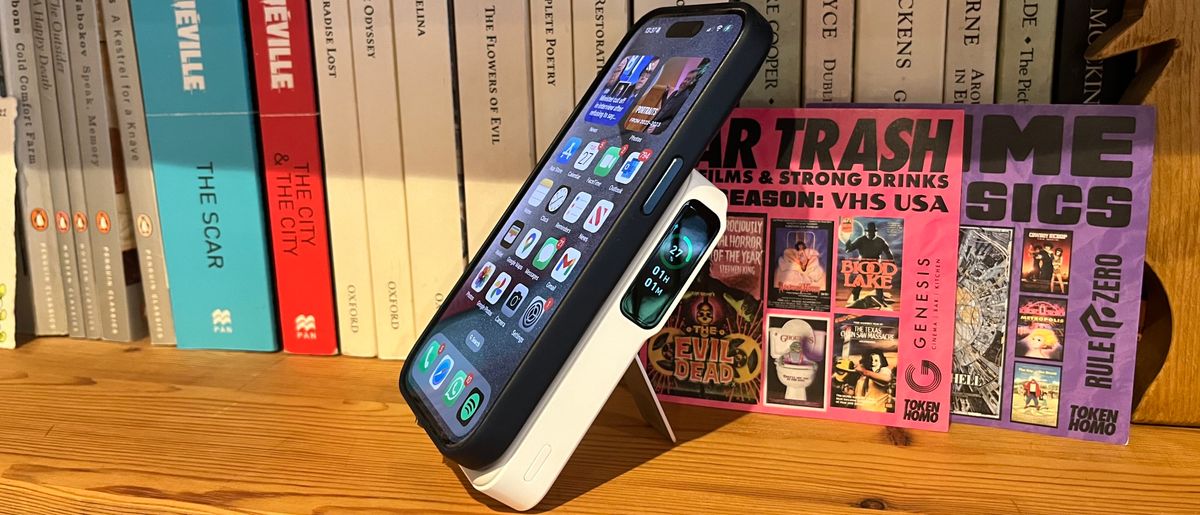 The Anker MagGo Power Bank (10K) connected to an iPhone 15 Pro on a wooden bookshelf