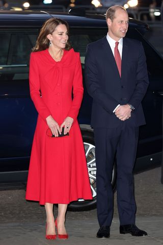 Kate Middleton wears a red coat and heels, alongside Prince William at the "Together at Christmas" community carol service on December 08, 2021 in London, England.