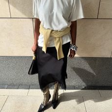 Marilyn Nwawulor-Kazemaks wearing a white tee, black lace-trim skirt, and yellow sweater. 