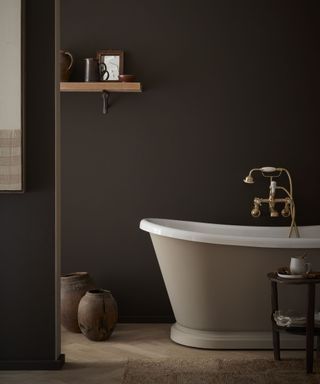 Bathroom painted dark chocolate brown with a warm beige bathtub