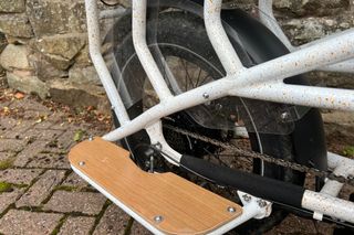 This image shows a closeup of the rear of the bike with the wheel, frame and footrests on display