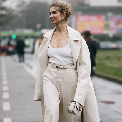 a milan fashion week fall winter 2025 attendee wearing white tank top beige coat and beige pants 