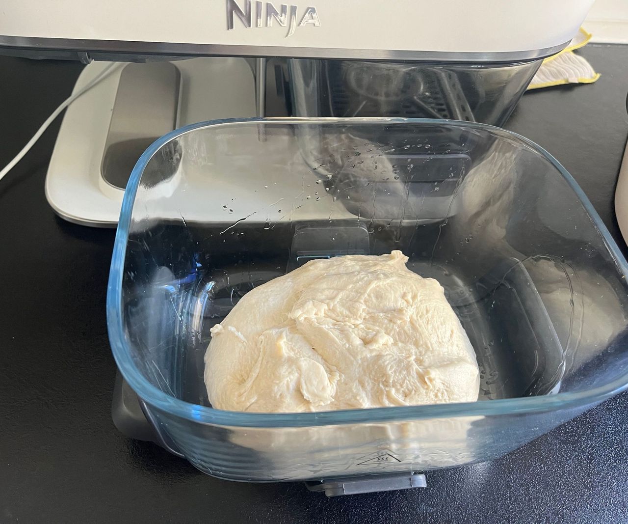 A small batch of raw bread dough in an oiled glass air fryer basket