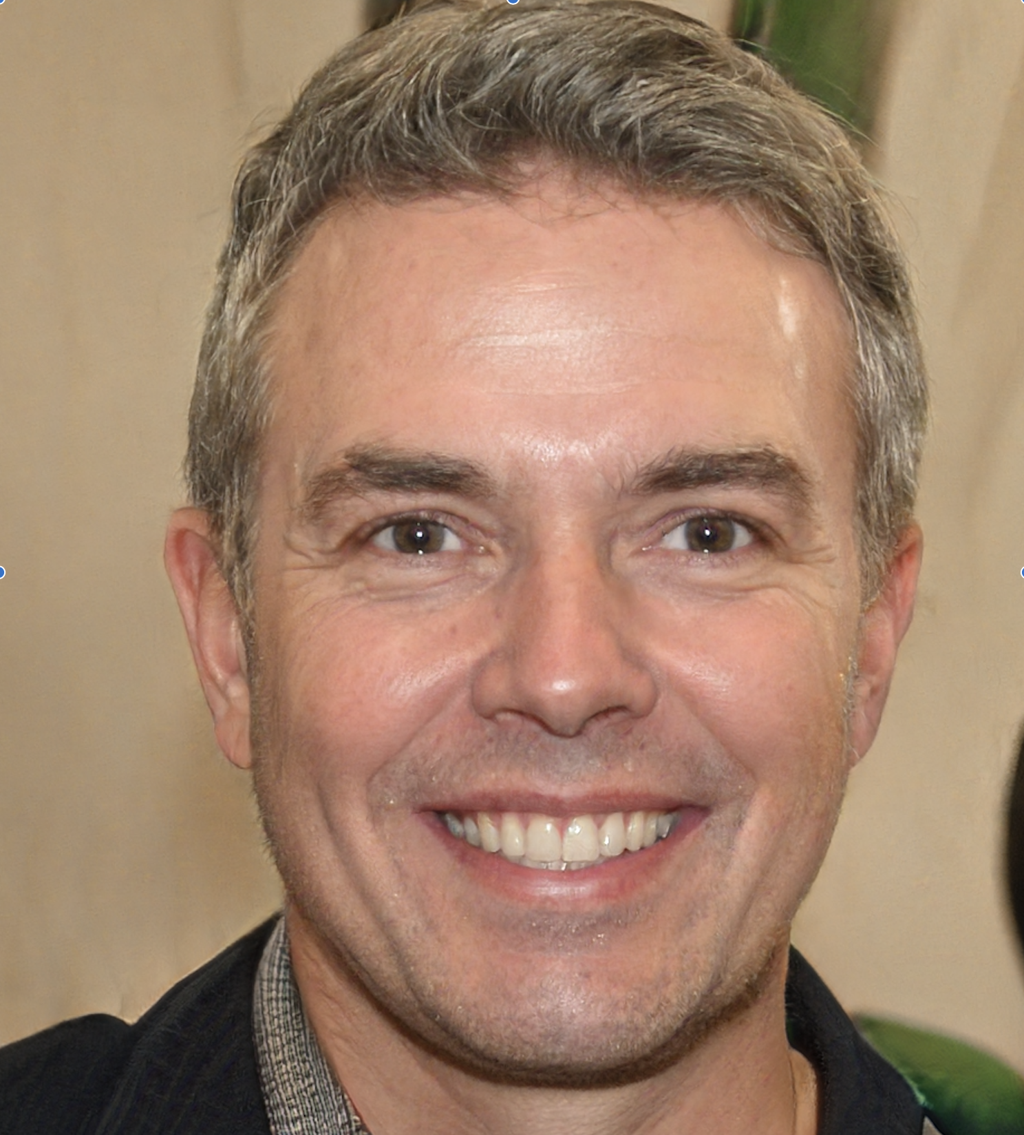 Headshot of a man with salt and pepper grey hair and dark collared top