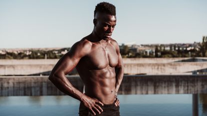 How to lose belly fat: Pictured here, an African-american athlete with visible abs posing in the setting sun